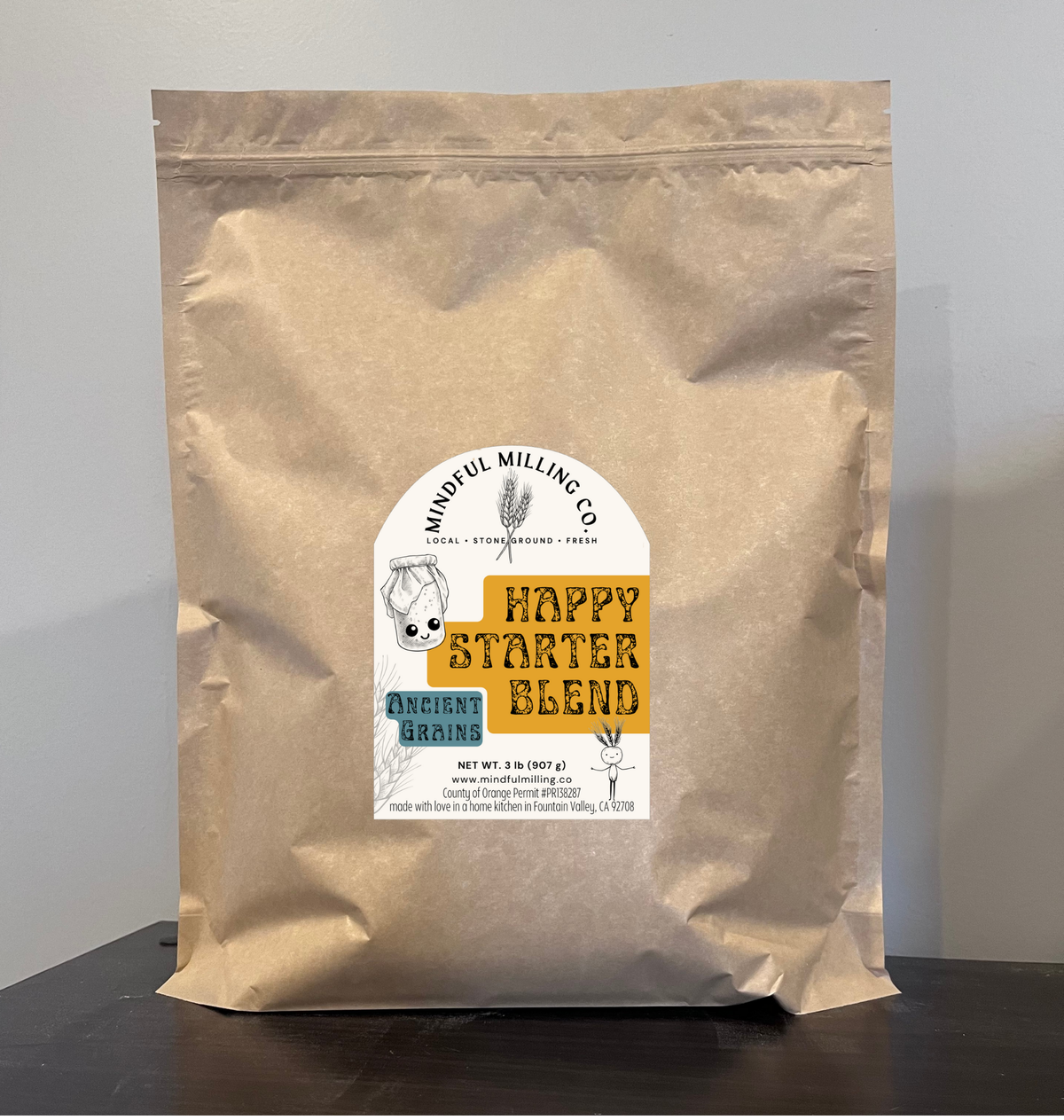 Kraft paper bag with a label for 'Happy Starter Blend' on a gray background