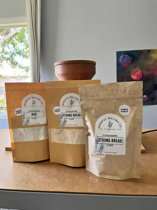 Three bags of Mindful Milling Co. flour lined up next to eachother. 